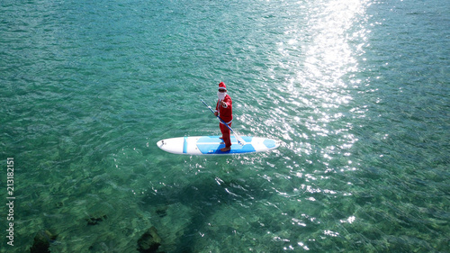 Canvas Print Aerial drone of Santa Claus paddle surfing in Caribbean turquoise clear waters