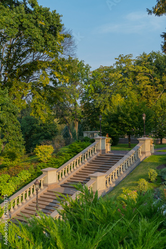 concrete stairs up in a green park with railing and lanterns on the pillars