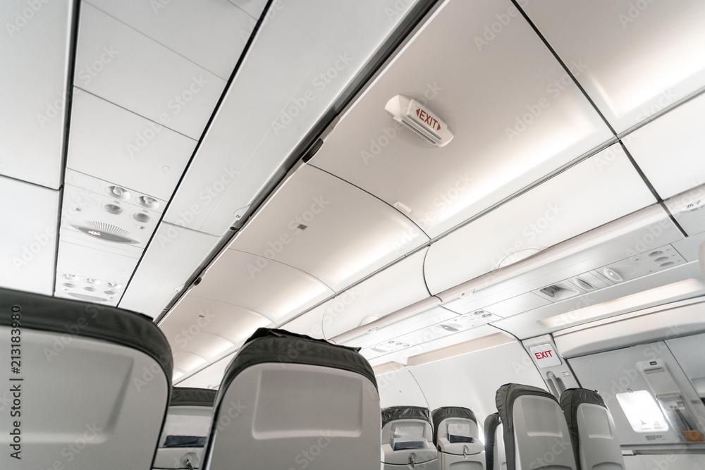 Obraz premium Emergency exit on an aircraft, view from inside of the plane. Empty airplane seats in the cabin. Modern Transportation concept. Aircraft long-distance international flight
