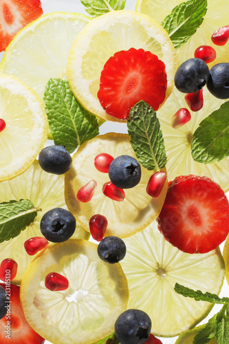 Fototapeta Naklejka Na Ścianę i Meble -  Ingredients sliced lime, lemon, strawberry, blueberries, seeds of pomegranate and mint  for fresh aromatic water drink. Summer detox concept.