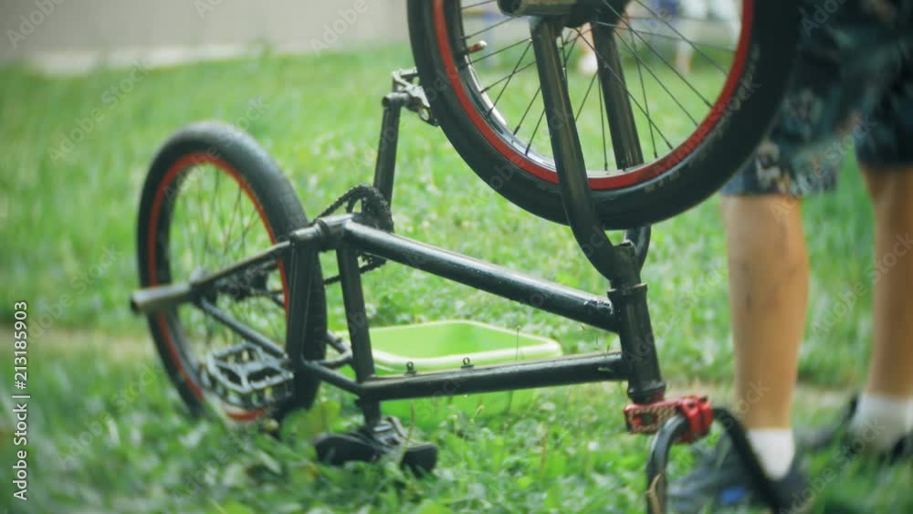 The boy washes his BMX bicycle with water and foam The boy washes his BMX bicycle with water and foam