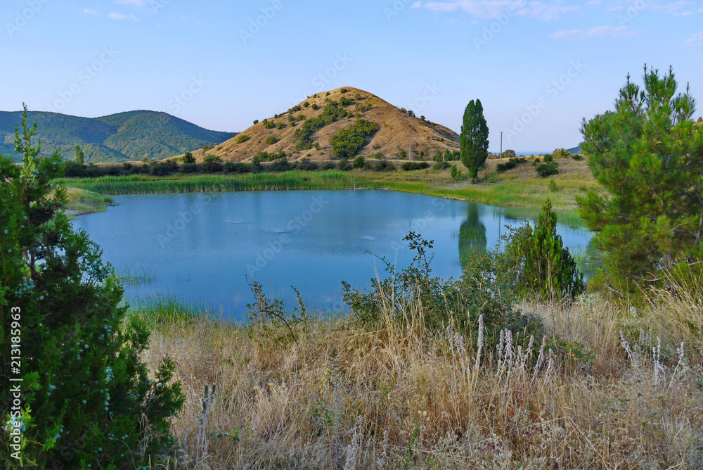 Charming small lake with clear blue water located in a picturesque area at the foot of the hill.