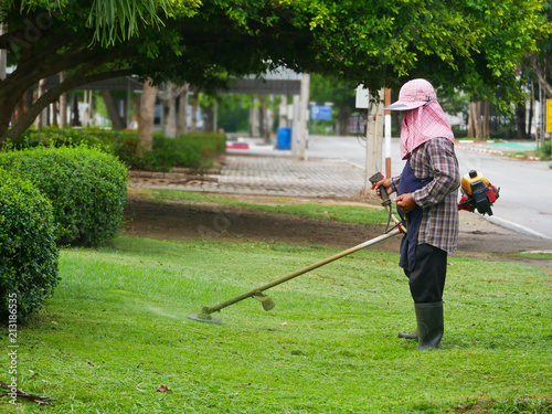 Man worker with a manual lawn mower mows the grass