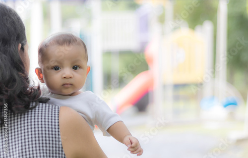 mother carries child in summer park, cute asian baby boy.