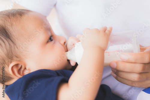 infant baby on being fed by her mother drinking milk from bottle.asian newborn