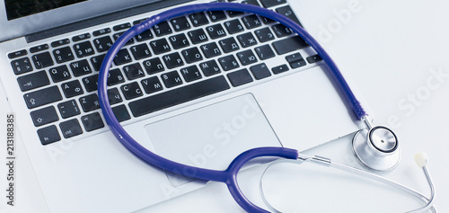 Stethoscope lying on a laptop keyboard in a concept of online medicine or troubleshooting the computer viewed low angle with copy space