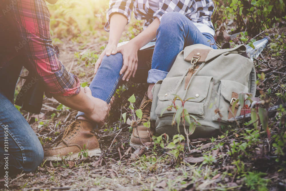 Naklejka premium Asian young couple travelers to hiking ankle injury on a green background, Hiking concept.