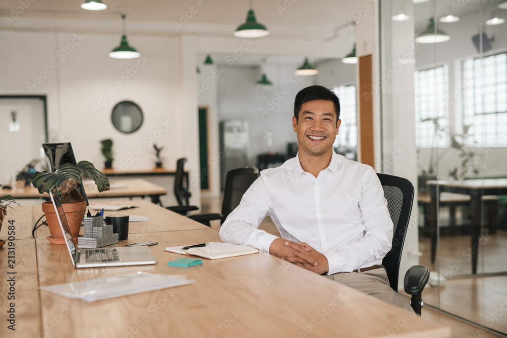 Smiling Asian businessman working at his desk in an office