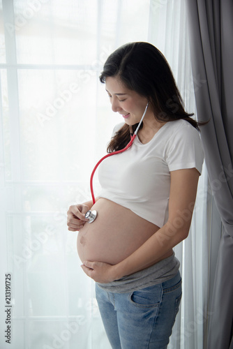 Happy Asian pregnant woman using stethoscope in the bedroom. Free Download Happy Asian pregnant woman using stethoscope in the bedroom. - GFXLoad