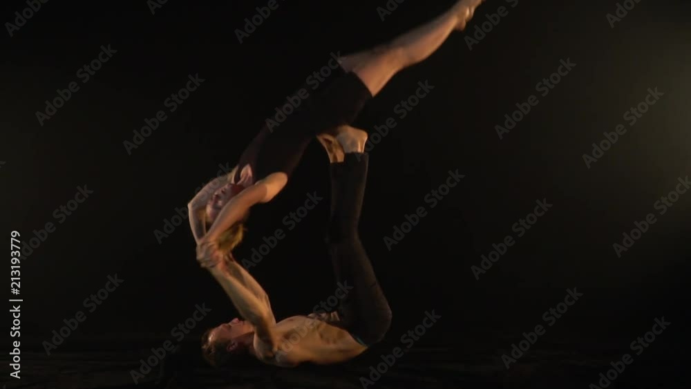 The couple performs tricks of acro yoga in the studio, a man throws up a woman The couple performs tricks of acro yoga in the studio, a man throws up a woman