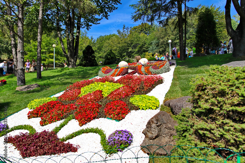 Beautiful composition on a slope in a park planted from flowers. With a lot of people on vacation at the top of the slope.