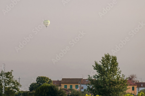 Hot air balloon flying over the Tuscan countryside in the first light of the day