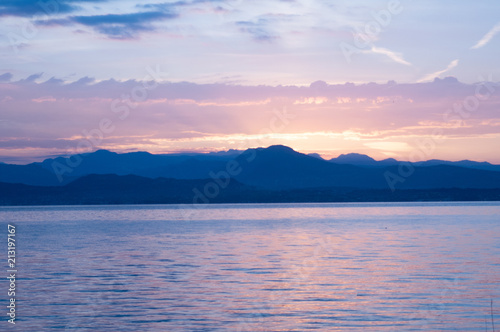 Sunrise on the lake. Early morning landscape. mountain in  silhouettes and the rays of the rising sun.Sunrise on Lake Garda  Italy.