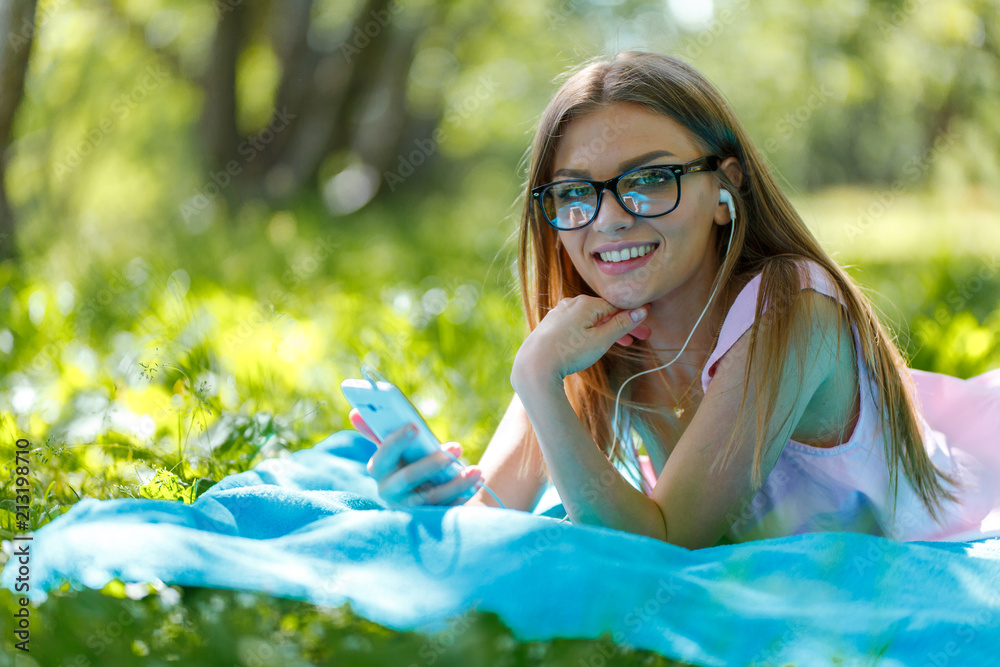 Woman lay down or relaxing on green grass listening music with smartphone in summer or spring Woman lay down or relaxing on green grass listening music with smartphone in summer or spring