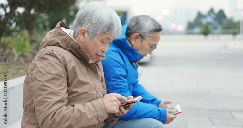 Old couple using smart phone together at outdoor street © leungchopan