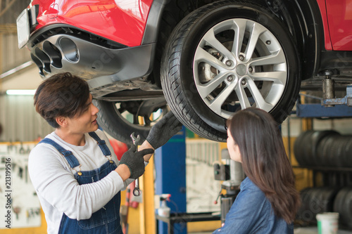 A mechanic showing the tread of a tire to a female customer