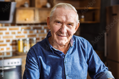 Portrait of pleasant aged man standing in the kitchen