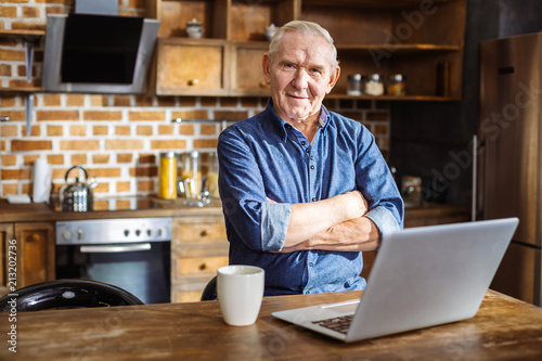 Pleasant eldelry man standing in the kitchen