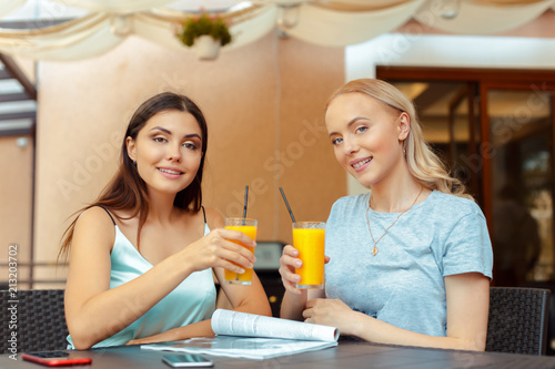 Two beautiful young girls sitting by the table in cafe