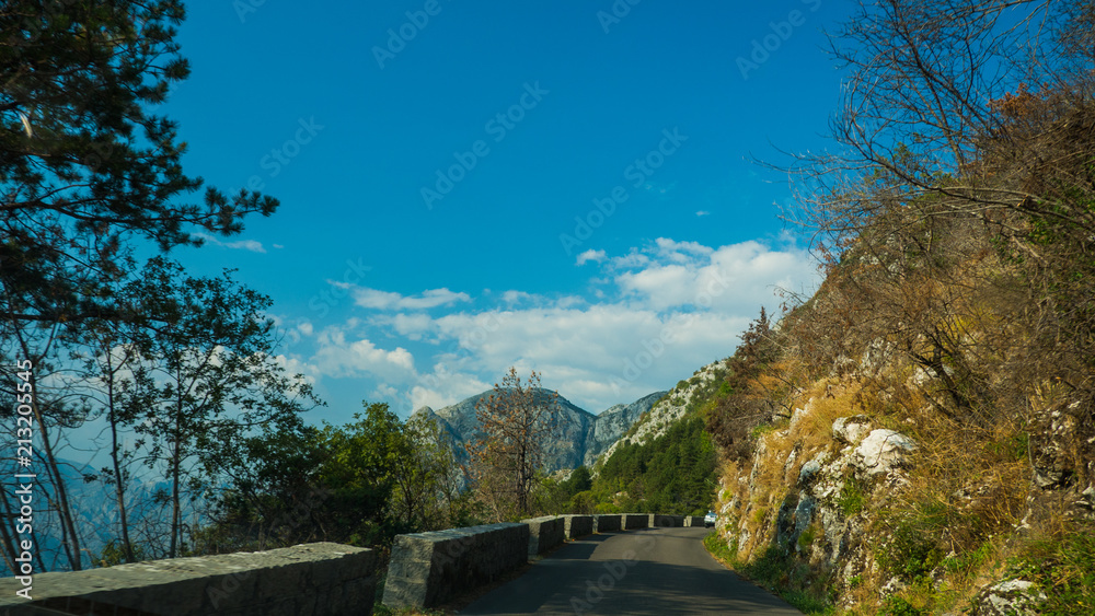 Fototapeta premium Mountain road with sharp turns, old brick fence and vegetation on the sides