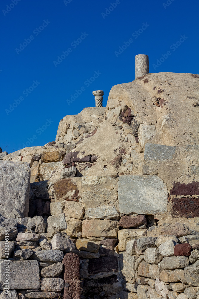 Typical old stone masonry view scene on Santorini. Fira, Greece, from below. Image taken from public path walk in the morning with clear blue sky as a contrast