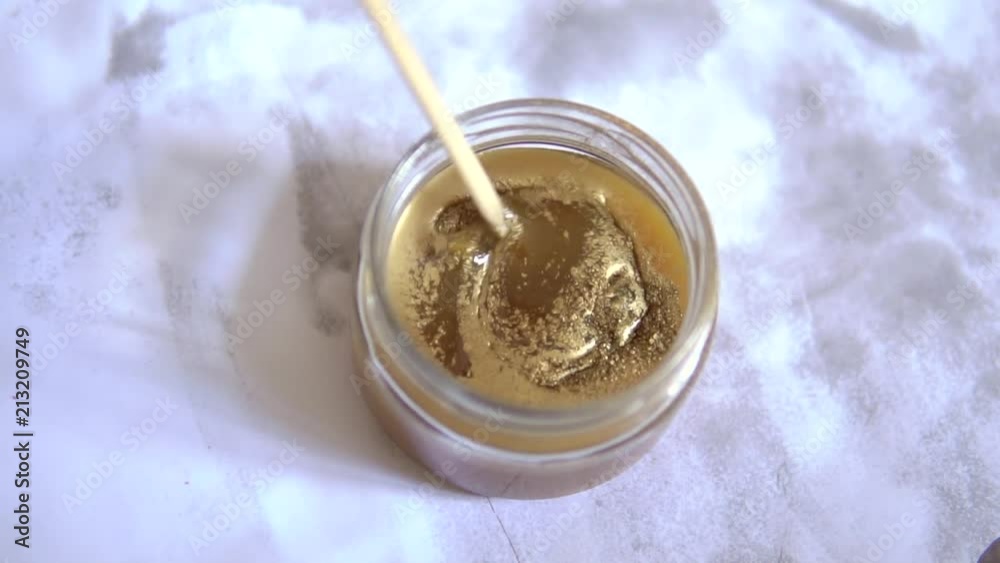 stir the bronze paint in a glass jar. stir the bronze powder in the paint solvent. yellow paint. brown paint. on white background. stir the bronze paint in a glass jar. stir the bronze powder in the paint solvent. yellow paint. brown paint. on white background.