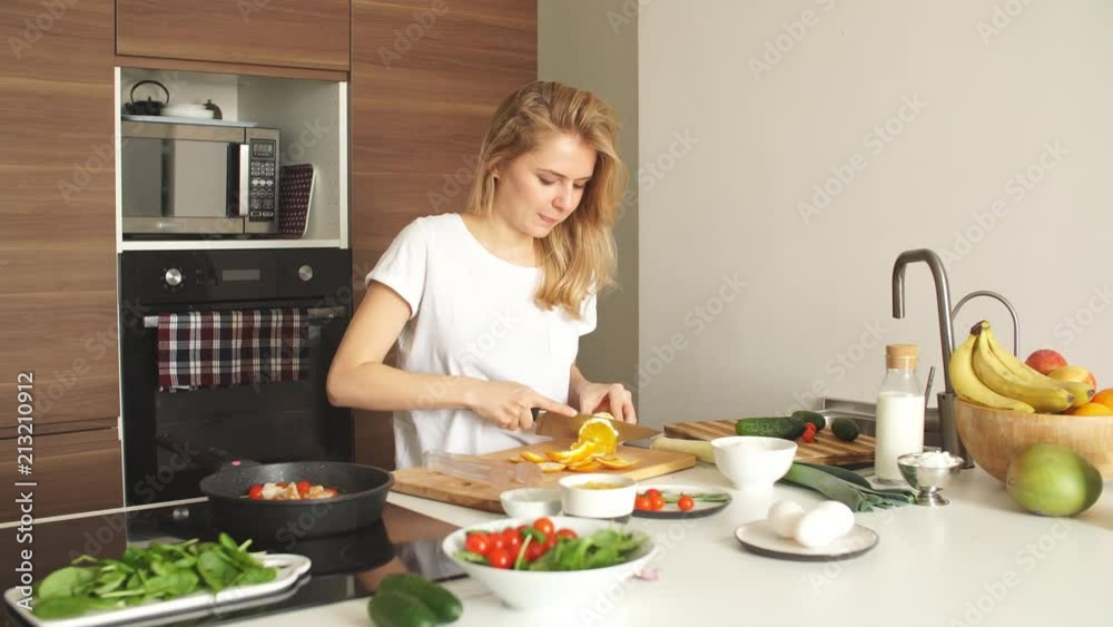 Portrait of happy female wife in white t-shirt cooking dinner at kitchen Portrait of happy female wife in white t-shirt cooking dinner at kitchen