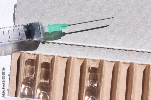 Novocaine in ampoule in the box and syringe on the table.
 photo