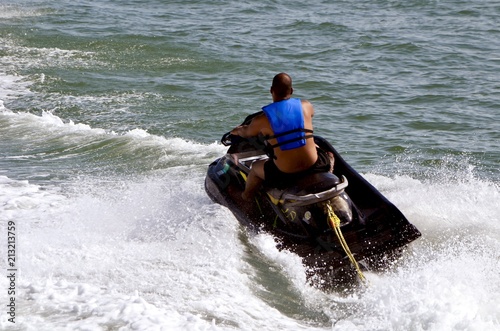 Angled overhead view of a man riding waves  on a black jet ski