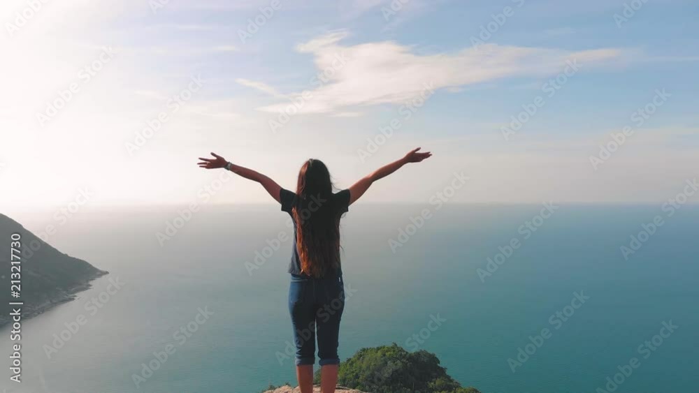 Woman with arms on top of mountain looking at Sunset view Hiker Girl lifting arm up celebrating life scenic nature landscape enjoying vacation travel adventure Woman with arms on top of mountain looking at Sunset view Hiker Girl lifting arm up celebrating life scenic nature landscape enjoying vacation travel adventure