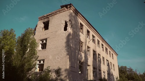 The house after the bombing, the house in the war, the hole from the shell in the wall, broken Windows, abandoned. photo