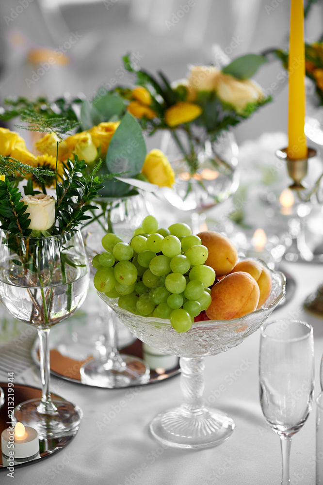 Vase with apricots and grapes on a high stem. Juicy fruit Vase with apricots and grapes on a high stem. Juicy fruit