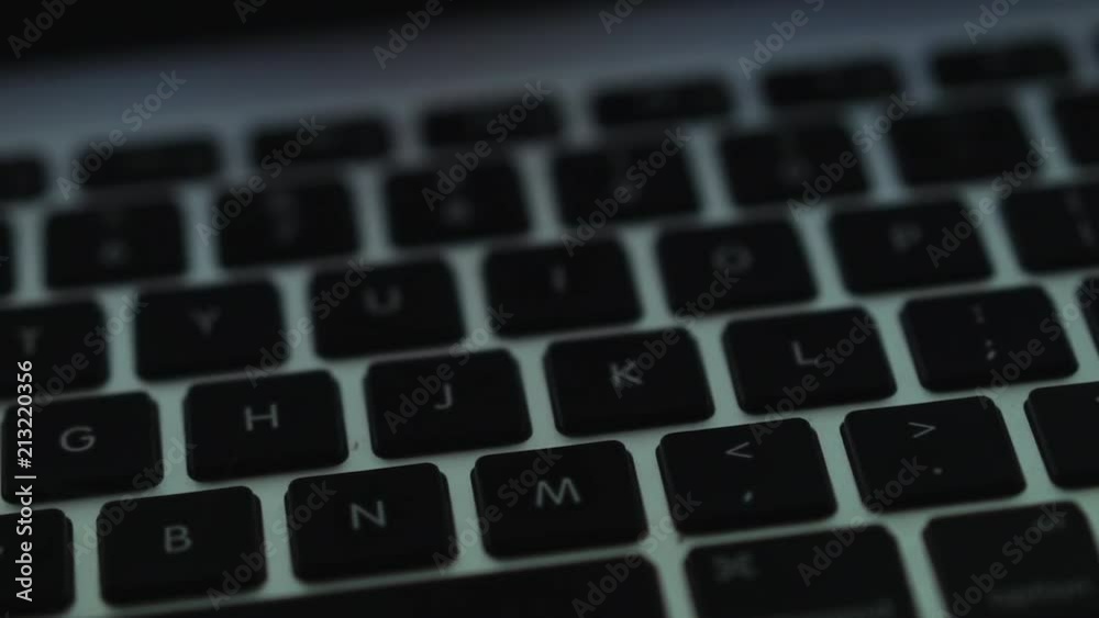 A laptop keyboard at night being lit by the screen. A laptop keyboard at night being lit by the screen.