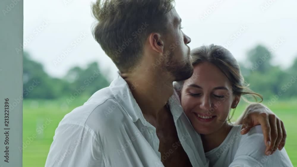 Medium shot of affectionate Caucasian couple embracing each other on balcony when spending time together Medium shot of affectionate Caucasian couple embracing each other on balcony when spending time together