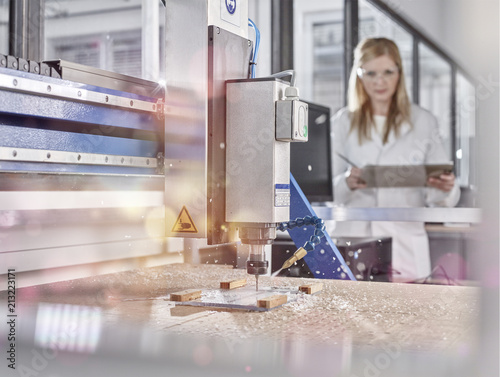 Female technician controlling CNC milling machine photo