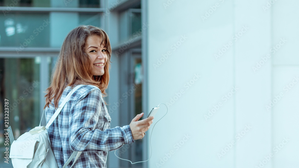 smiling college girl with back pack holding cell phone looking at camera. large copy space smiling college girl with back pack holding cell phone looking at camera. large copy space