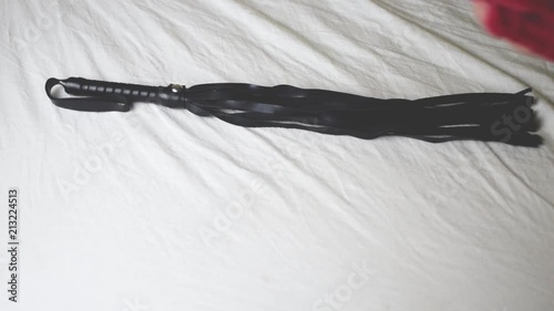 Toys for erotic games BDSM. A whip, handcuffs, clamps lie on the bed.