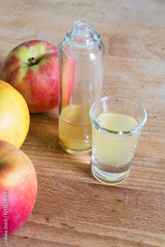 Obraz na płótnie portrait of bottle and glass filled with naturally cloudy apple cider vinegar with apples as decoration on wooden table w salonie