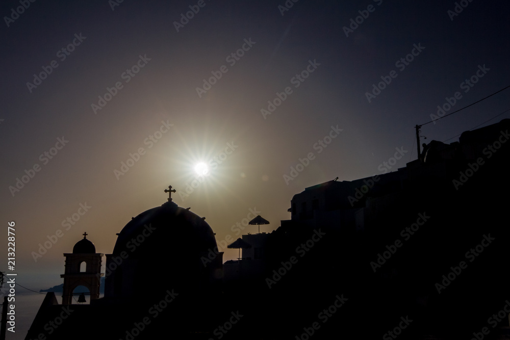 Romantic sunset silhouettes scene, Santorini, Greece. Shortly before the sunset, church in the front. Typical architecture for this travel destination island. Sun rays diffraction