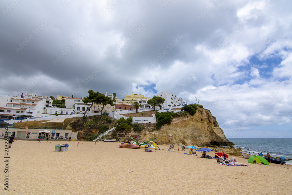 turistas en la playa  del pueblo de Carvoeiro con coloridas casas, región de Algarve, Portugal