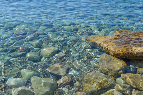 Marine background. Quiet Adriatic Sea. Blue clear water and large stones.