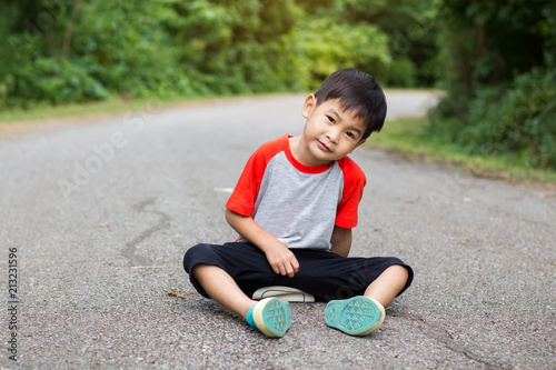 Young asian cute boy sitting and looking on road in park.