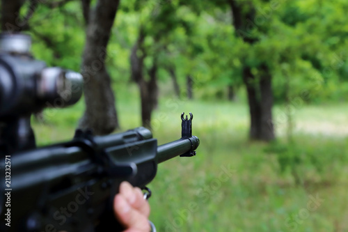 The hunter is aiming at the gun. Sighting the gun barrel at the target.