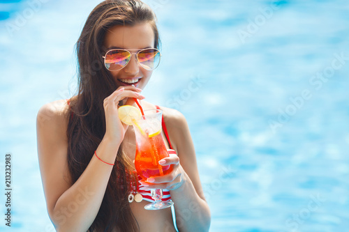 Very beautiful young woman in the swimming pool drinking cocktail