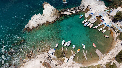 Aerial drone bird's eye view photo of picturesque small fishing harbor of Mandrakia with boat houses called syrmata and fishing boats docked on turquoise clear waters, Milos island, Cyclades, Greece photo