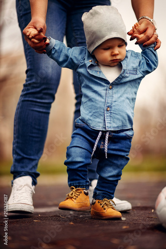 Mother is helping her boy taking his first steps photo