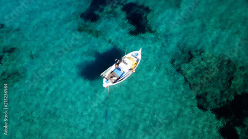 Aerial drone bird's eye view photo of traditional fishing boat docked in port of Polonia with turquoise clear water sea, Milos island, Cyclades, Greece