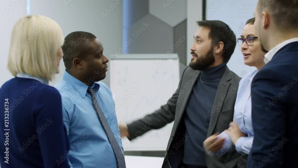 Cheerful asian businessman telling something to multiethnic group of colleagues in the office Cheerful asian businessman telling something to multiethnic group of colleagues in the office