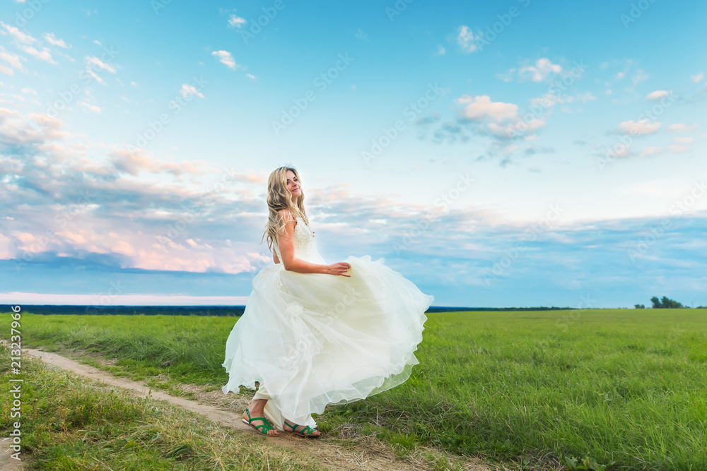 Young blonde woman bride spinning outdoors on fild Young blonde woman bride spinning outdoors on fild