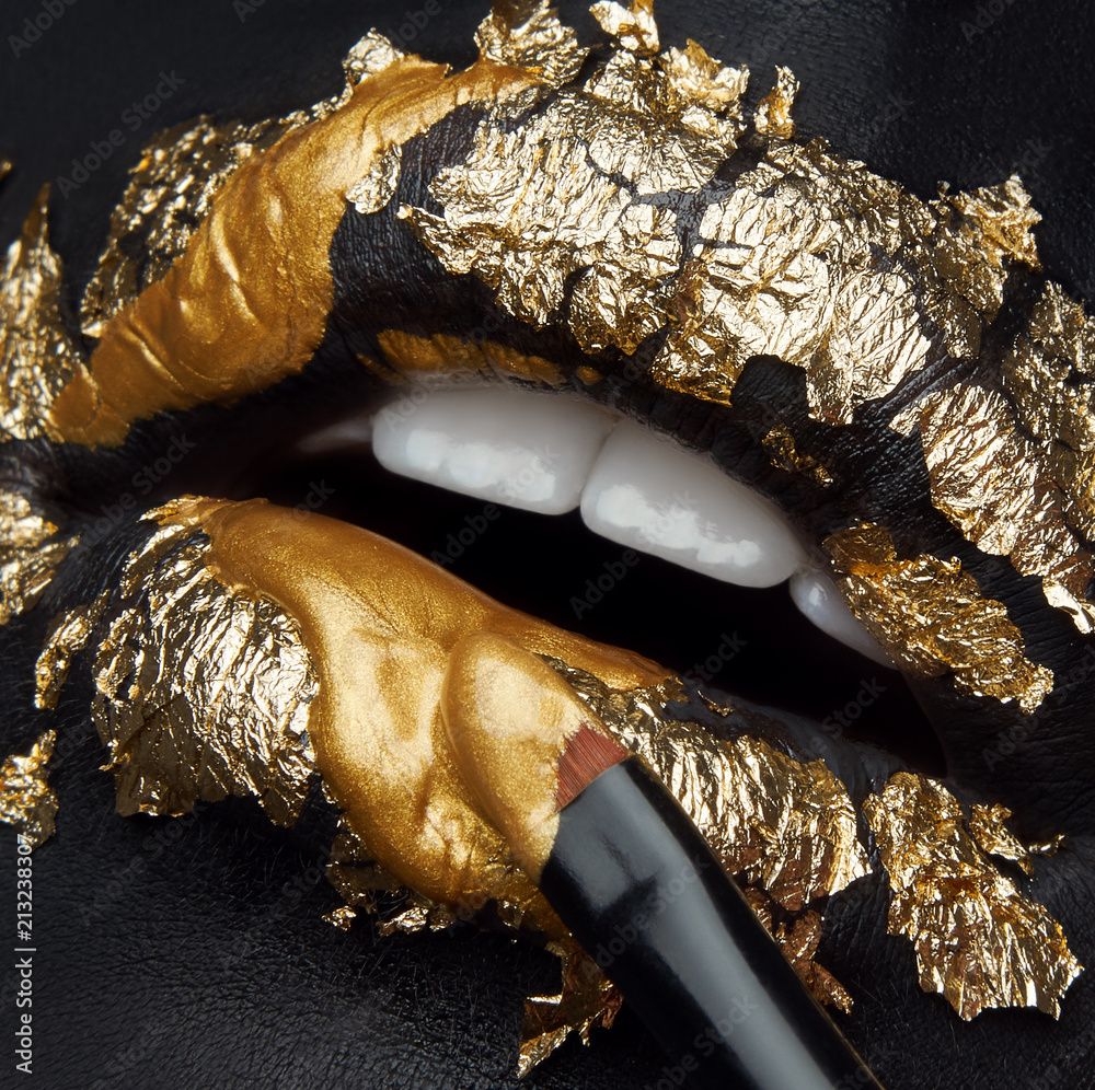 Obraz premium Macro and close-up creative make-up theme: beautiful female lips with black leather and gold foil and gold paint and brush